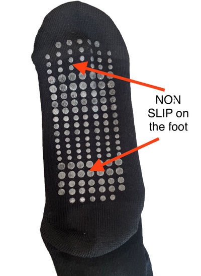 Black non-slip sock with textured sole on a gray carpet background